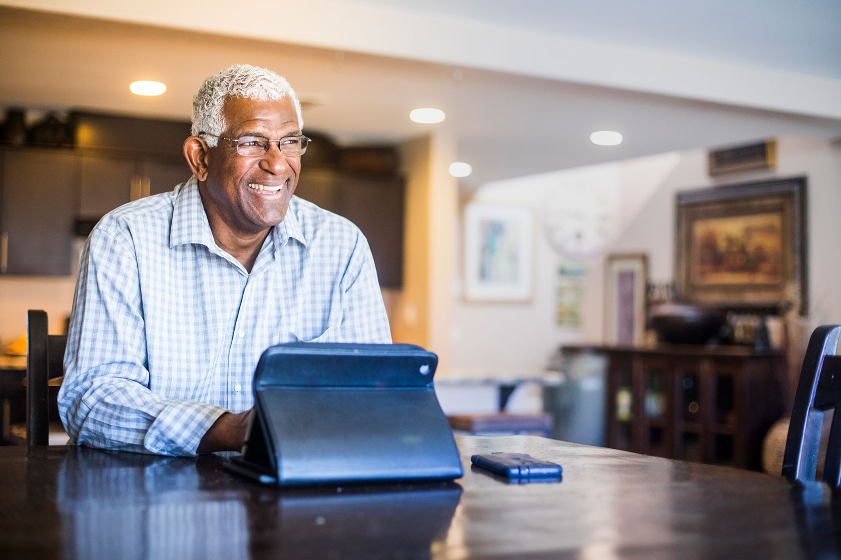 Older black man smiling while looking at tablet