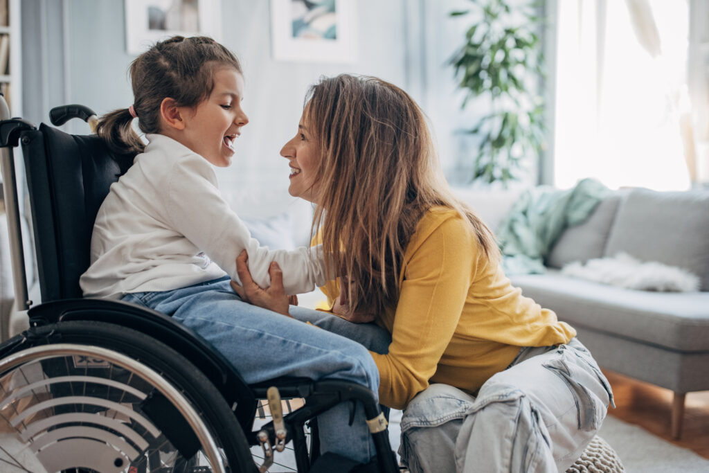 Mother and young daughter in wheelchair at home